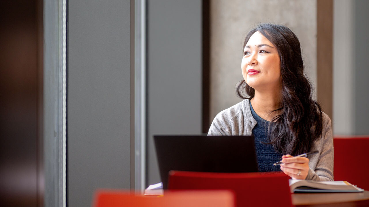 Woman looking off into the distance with her laptop on a table